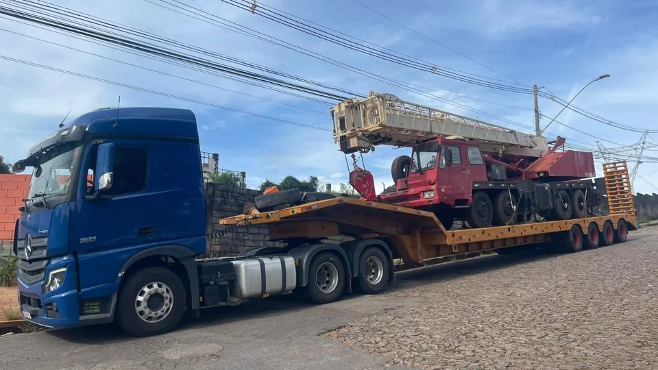 Caminhão Mercedes Actros azul transportando grua sobre rodas em prancha de quatro eixos