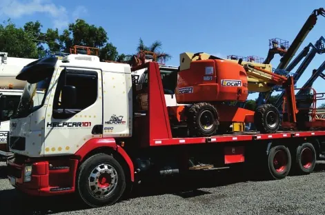 Caminhão Volvo branco e vermelho da HELPCAR 101 carregado com plataforma elevatória JLG