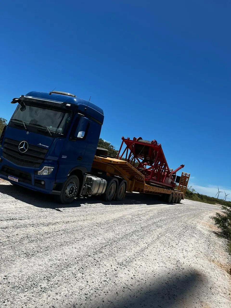 Caminhão Mercedes Actros azul com equipamento industrial em estrada de parque eólico