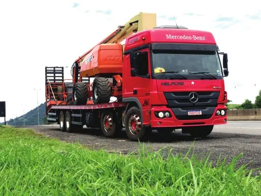Caminhão Mercedes Atego vermelho da HELPCAR 101 transportando plataforma articulada JLG